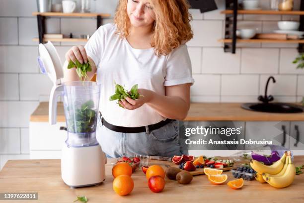 ritratto di una bella donna sorridente che prepara frullato in cucina a casa. - grasso nutrienti foto e immagini stock