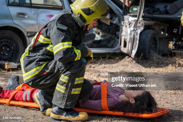 firefighter or rescue helping an injured woman after a car accident. - victim assistance stock pictures, royalty-free photos & images