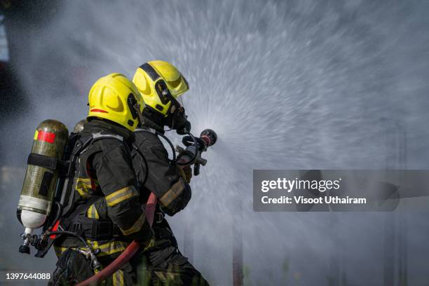 firefighter fighting fire,two firefighters water spray by high pressure nozzle in fire fighting operation. - fighting forest fire stock pictures, royalty-free photos & images