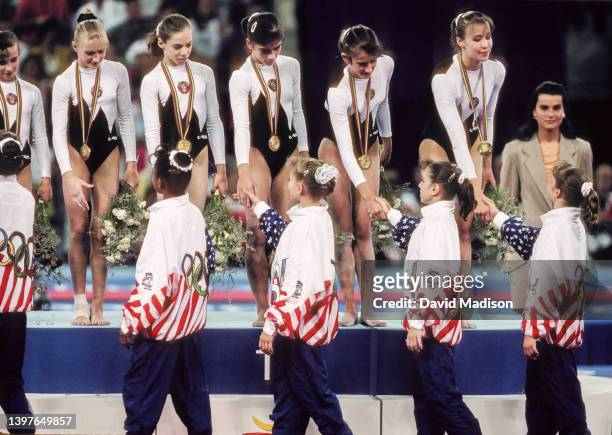 The Unified team shake hands with the USA team after receiving their gold medals on July 28, 1992 during the Team All-Around event of the Women's...