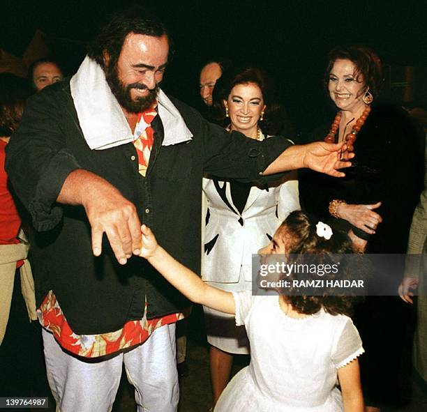 Italian Tenor Luciano Pavarotti dances with a Lebanese girl upon his arrival at Beirut airport 10 June 1999 while Nazik Hariri wife of former prime...