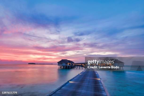 amazing sunset panorama at maldives. luxury resort villas seascape with soft led lights under colorful sky. beautiful twilight sky and colorful clouds. beautiful beach background for vacation holiday - maldivas fotografías e imágenes de stock