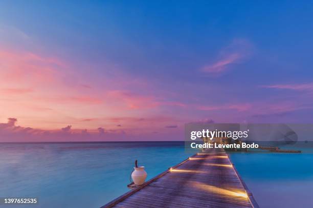 sunset on maldives island, luxury water villas resort and wooden pier. beautiful sky and clouds and beach background for summer vacation holiday and travel concept. paradise sunset landscape - bungalow stock pictures, royalty-free photos & images