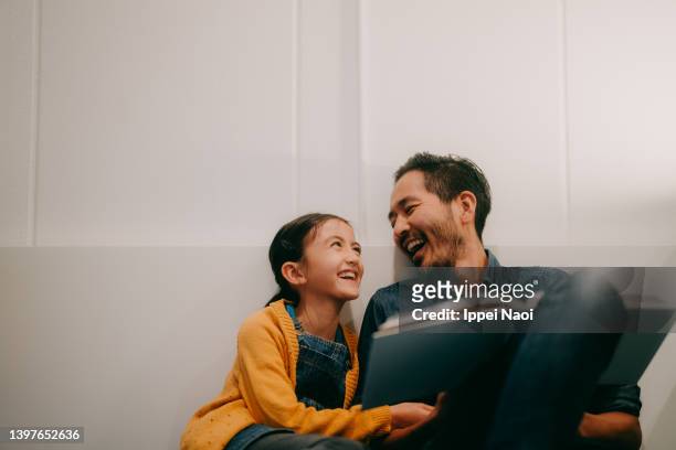 father and young daughter reading book together at home - kids read fotografías e imágenes de stock