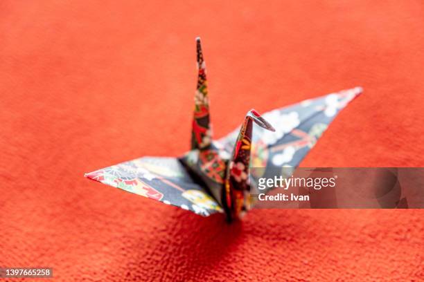 japanese style origami cranes against red background - papierkranich stock-fotos und bilder