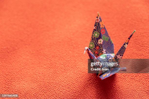 japanese style origami cranes against red background - origami a forma di gru foto e immagini stock