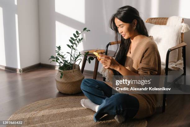 beautiful young woman with brown hair talking on phone, sitting on floor at home. distant work and education. freelanser concept - kazakhstan stock photos et images de collection