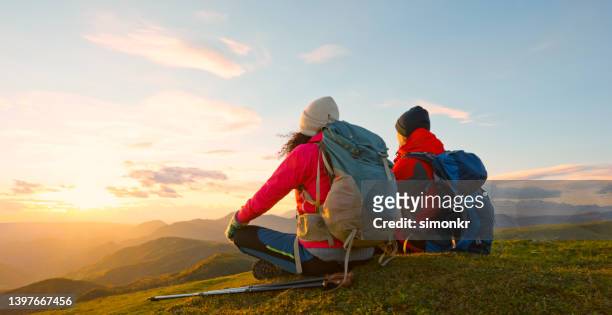 paar sitzt auf dem gipfel des berges - red couple stock-fotos und bilder