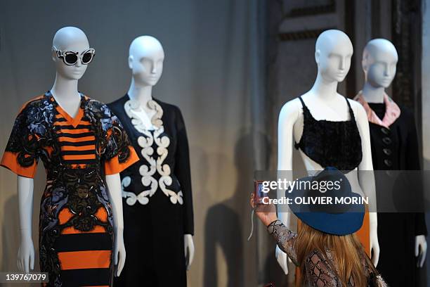 Journalist takes a pictures of iconic Prada ensembles during a press conference announcing the 'Schiaparelli and Prada: Impossible Conversations'...