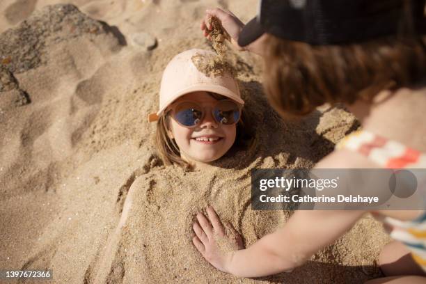 a 6 year girl sanding up her friend on the beach - bury fotografías e imágenes de stock