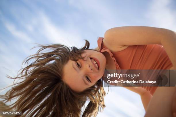 portrait of 6 year old girl smiling with her head upside down at the beach - badkläder bildbanksfoton och bilder