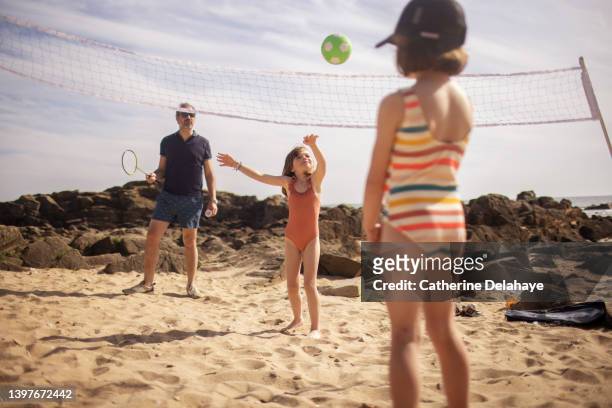 a family playing ball games on the beach - beach photos stock pictures, royalty-free photos & images
