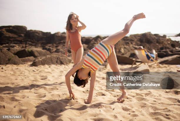 two 6 year old girl friends playing on the beach - acrobatic activity stock-fotos und bilder