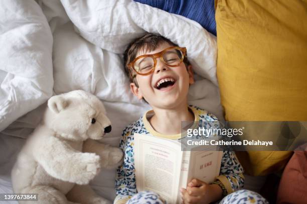 a 4 year old little boy having fun, laying on a bed - reading stock-fotos und bilder