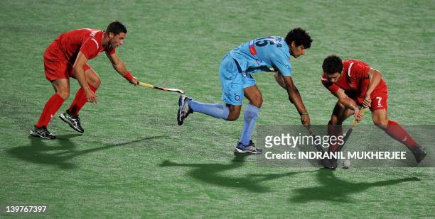 Uthappa Sannuvanda Kushalappa of India dribbles past Szymon Oszyjcczyk and Tomasz Gorny of Poland during the men's field hockey match between India...