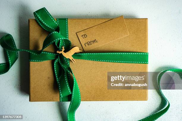 overhead view of a gift box decorated with a green ribbon, pinecones, reindeer ornament and gift tag - gift tag and christmas stockfoto's en -beelden