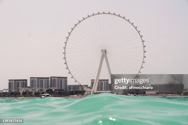 view of ain dubai ferris wheel and city skyline from jumeirah beach, dubai, uae - hotel jumeirah beach fotografías e imágenes de stock