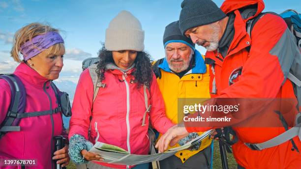 friends standing with map against sky - multi colored jacket stockfoto's en -beelden