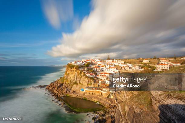 picturesque village azenhas do mar. holiday white houses on the edge of a cliff with a beach and swimming pool below. landmark near lisbon, portugal, europe. landscape at sunset. - azenhas do mar stock-fotos und bilder