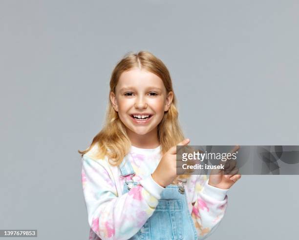 happy girl pointing against gray background - seven point stock pictures, royalty-free photos & images