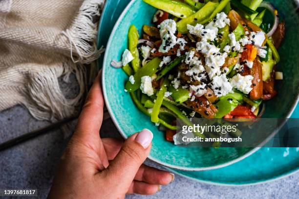 overhead view of a woman holding a bowl of greek salad - greek food imagens e fotografias de stock