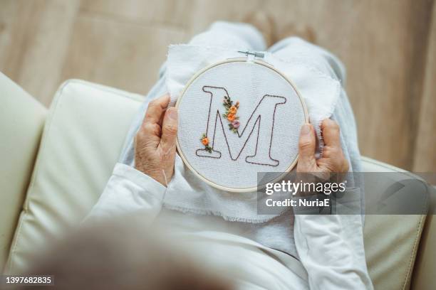 overhead view of a woman holding an embroidery hoop with the letter m - m a stock-fotos und bilder