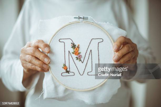 senior woman holding an embroidery hoop with the letter m - letter m 個照片及圖片檔