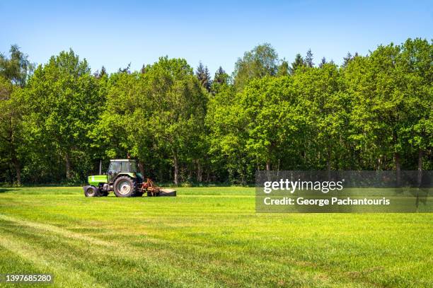 tractor on agricultural land surrounded by trees - champs tracteur photos et images de collection