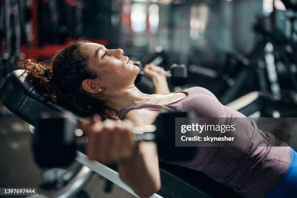 sportswoman exercising with dumbbell on a bench press in a gym. - weight stock pictures, royalty-free photos & images