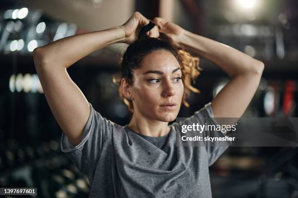 sportliche frau, die sich in einem fitnessstudio die haare bindet. - woman hair tied up stock-fotos und bilder