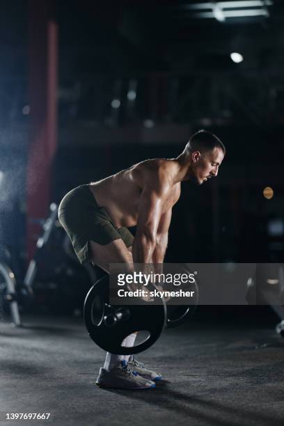 muscular build sportsman exercising with barbell in a gym. - snatch weightlifting stock pictures, royalty-free photos & images