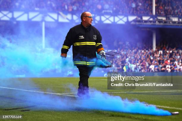 Smoke bomb is removed from the pitch during the Premier League match between Everton and Brentford at Goodison Park on May 15, 2022 in Liverpool,...