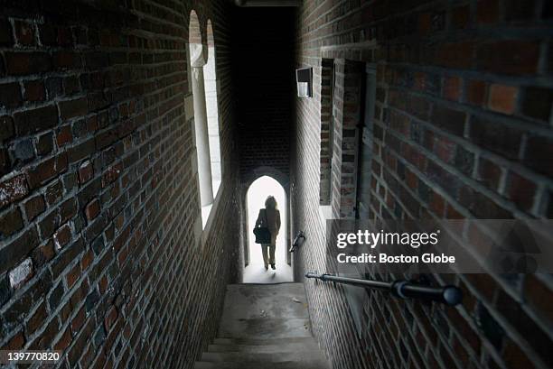 Woman is silhouetted as she walks through the arched doorway from an outside stairwell of Green Hall at the Wellesley College Campus.