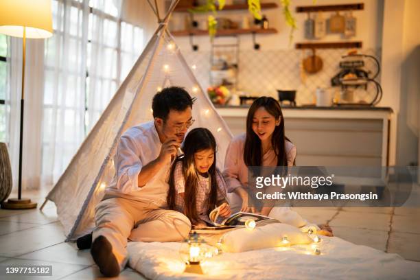 parents and daughter enjoying home - zelt nacht stock-fotos und bilder