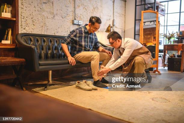 salesman measuring shoe size of a customer in a menswear clothing and shoe store - schoenenwinkel stockfoto's en -beelden