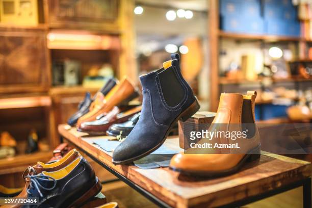 casual leather boots and shoes for men on a wooden shelf in a retail store - leather shoe stock pictures, royalty-free photos & images