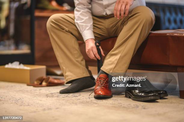 male customer trying on luxury leather shoes in a department store at the shopping mall - casual menswear stock pictures, royalty-free photos & images