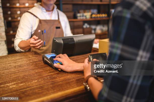 male adult customer buying with a credit card in a menswear clothing store - shoe shop assistant stock pictures, royalty-free photos & images