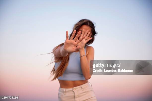 portrait of woman covering her face with her hand at sunset - scham stock-fotos und bilder
