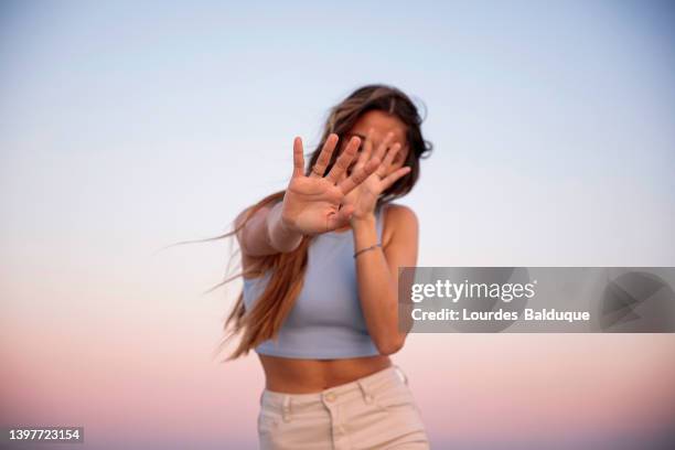 portrait of woman covering her face with her hand at sunset - shameful stock pictures, royalty-free photos & images