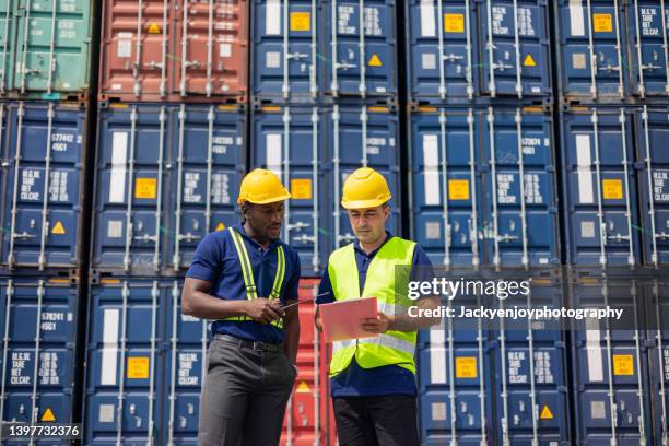 two commercial dock workers examining and confirm shipment at cargo container yard - commercial dock stockfoto's en -beelden