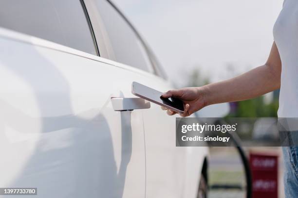 asian young woman is using smartphone to unlock car - auto tür offen stock-fotos und bilder