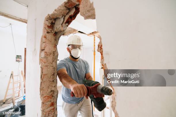 construction worker demolishing a brick wall - demolition of florida sinkhole house continues stockfoto's en -beelden
