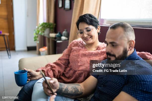 mid adult couple using the mobile phone at home - mid adult couple stock pictures, royalty-free photos & images