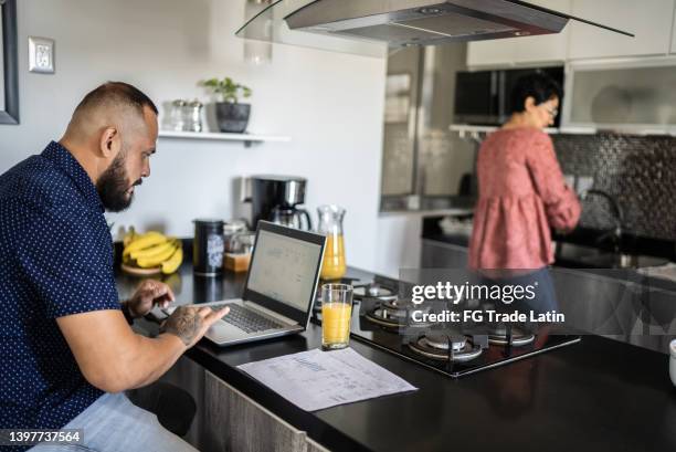 husband using the laptop and wife washing dishes at home - husband cleaning stock pictures, royalty-free photos & images