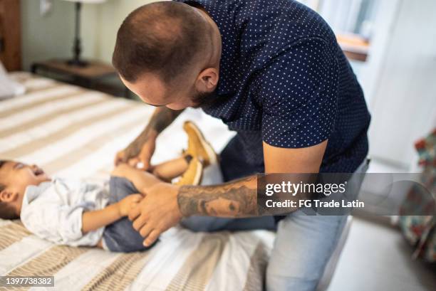 father changing his son clothes at home - changing nappy stock pictures, royalty-free photos & images