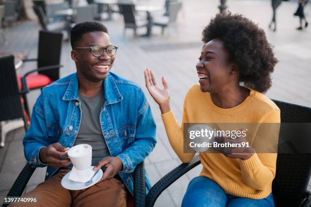 cheerful young couple enjoying a cup of coffee together - coffee shop couple stock pictures, royalty-free photos & images