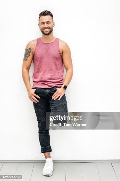 portrait of man with tank top and shoulder tattoo - pink pants stock-fotos und bilder