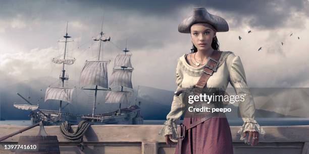 female pirate in period clothing standing on ships deck looking at camera - pirata imagens e fotografias de stock