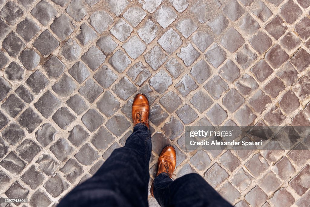 Walking on cobblestone street wearing leather shoes in Rome, directly above personal perspective view